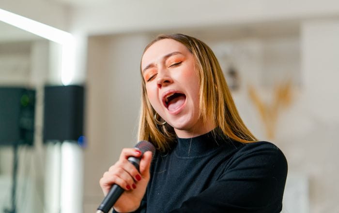 Young girl sings in a vocal lesson with a microphone.